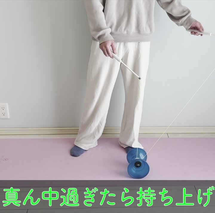 紐の中央を過ぎたディアボロをスティックで持ち上げる瞬間