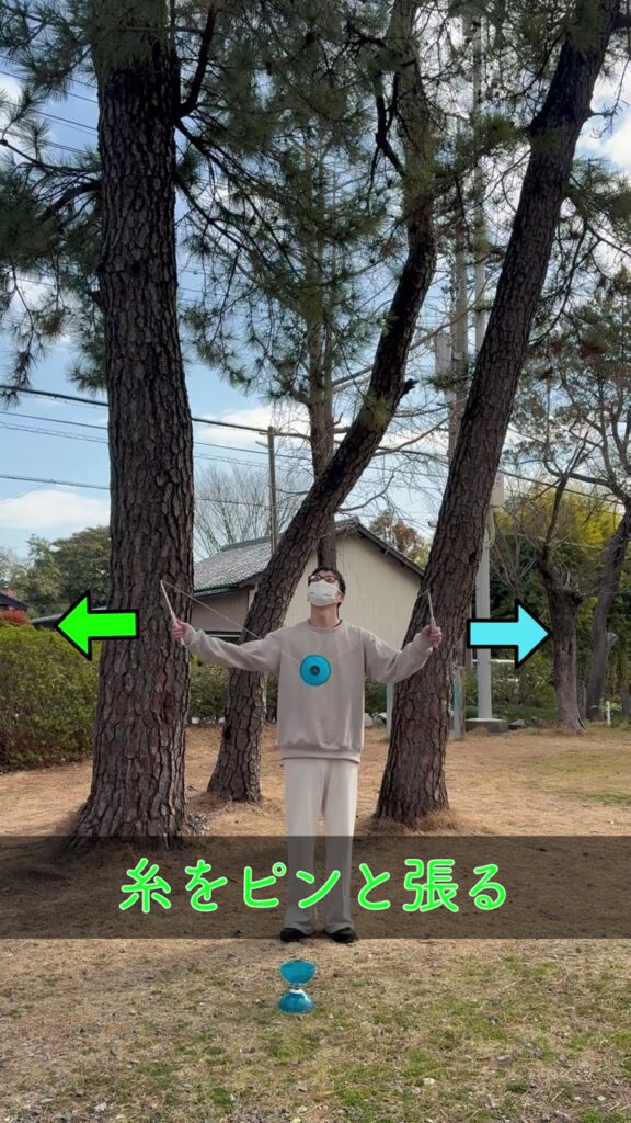 両手のスティックを左右に広げて糸をピンと張りディアボロを投げ上げる動作